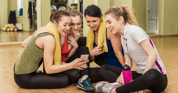 Gruppo di ragazze controllano instagram durante una pausa in palestra